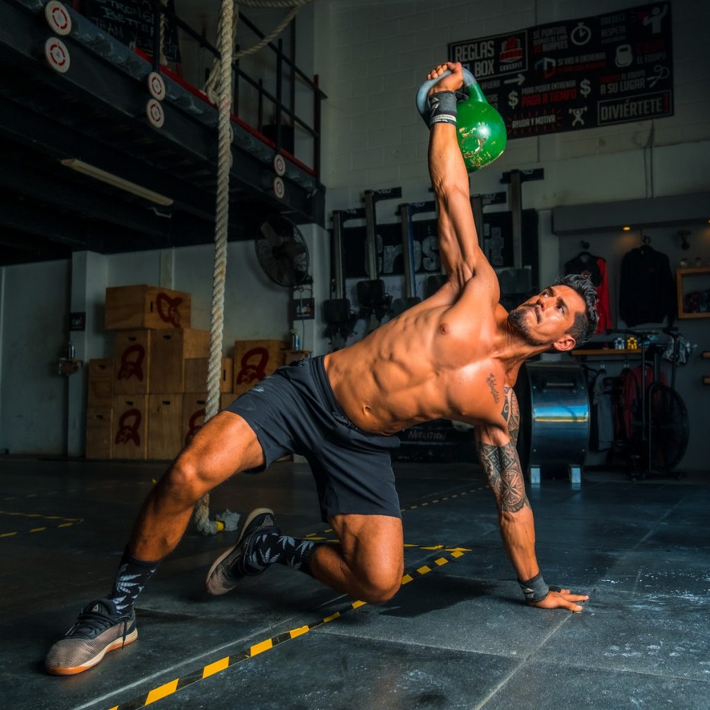 man in black shorts and black tank top doing push up