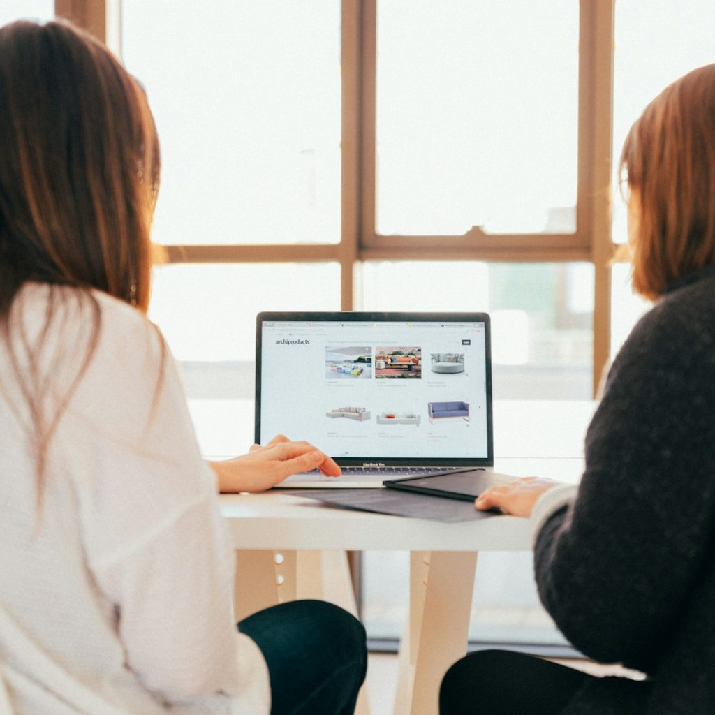 two women talking while looking at laptop computer