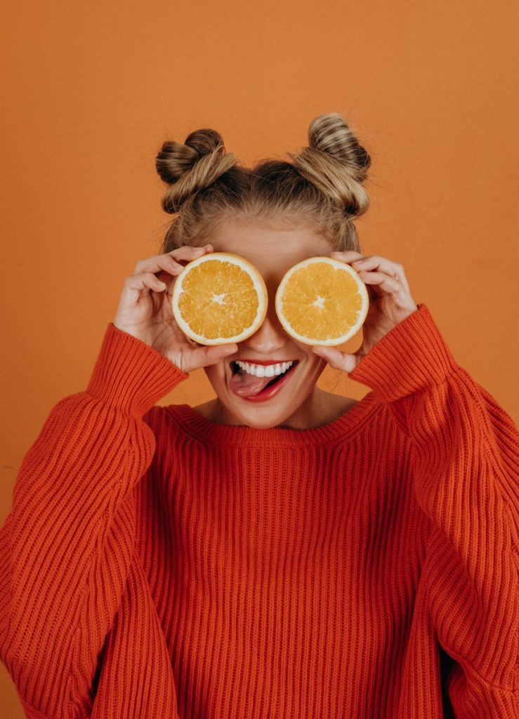 woman in red knit sweater holding lemon