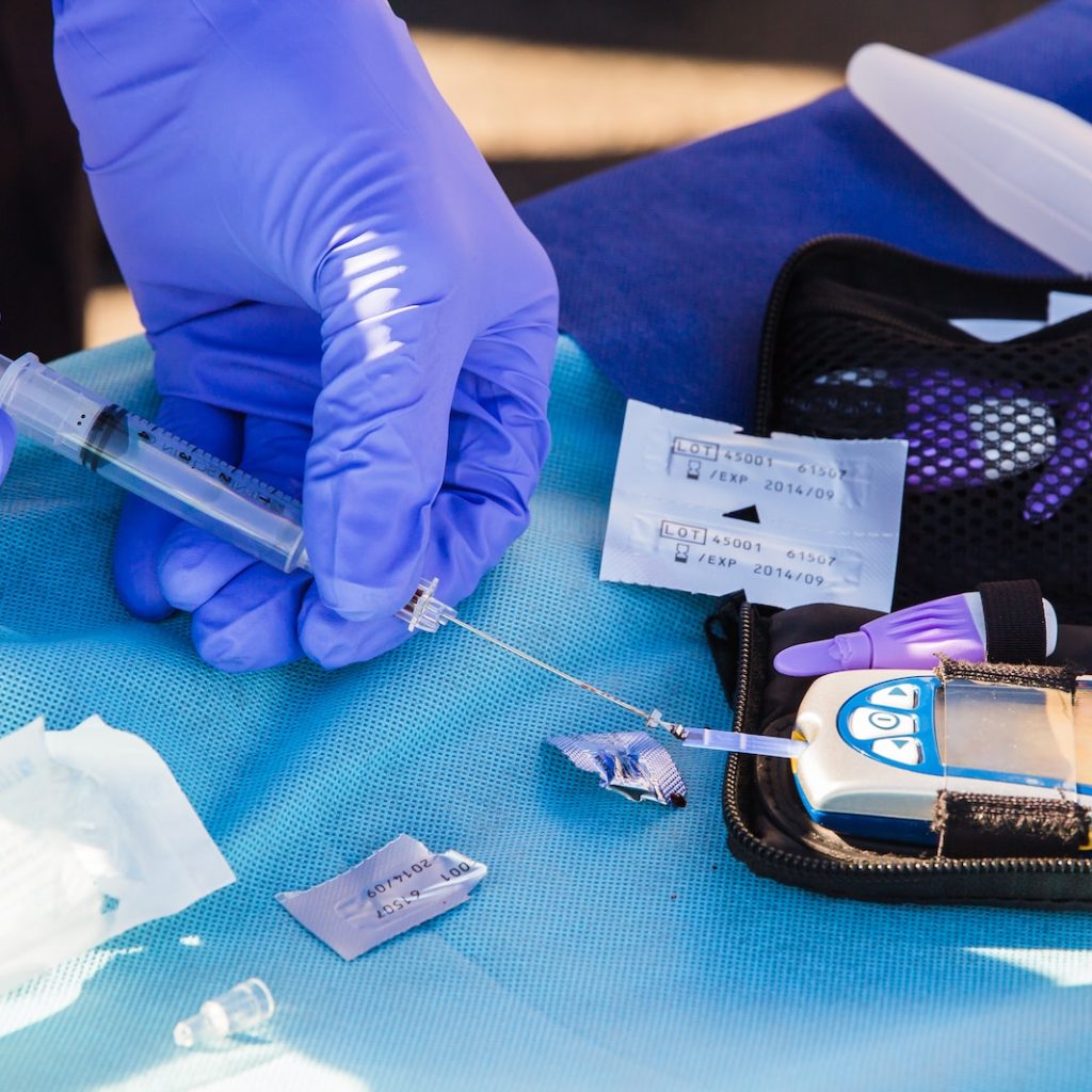 person using disposable syringe put specimen on blue and white glucose meter