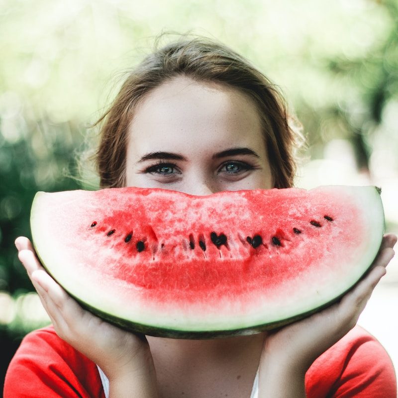 woman holding sliced watermelon